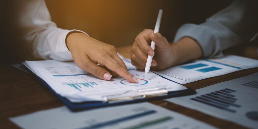 Two professionals reviewing financial and medical charts on clipboards with a pen, discussing additional documentation during long-term disability (LTD) insurance claim review process