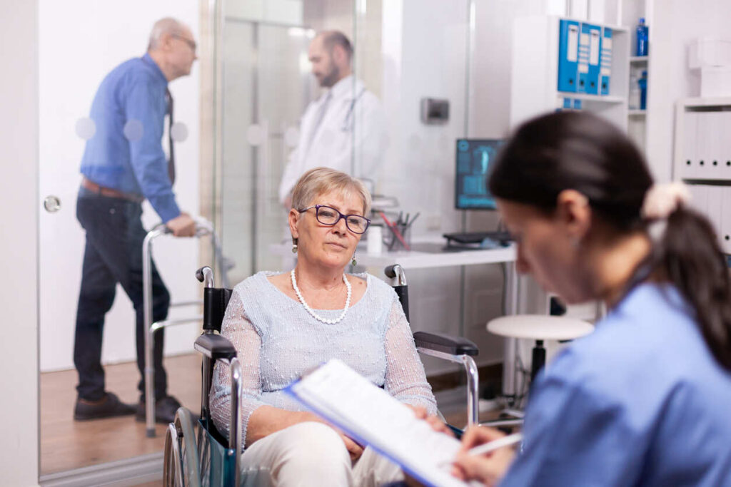 Patient in a wheelchair discussing their condition with a healthcare worker, symbolizing the medical evaluation phase of a long-term disability claim.