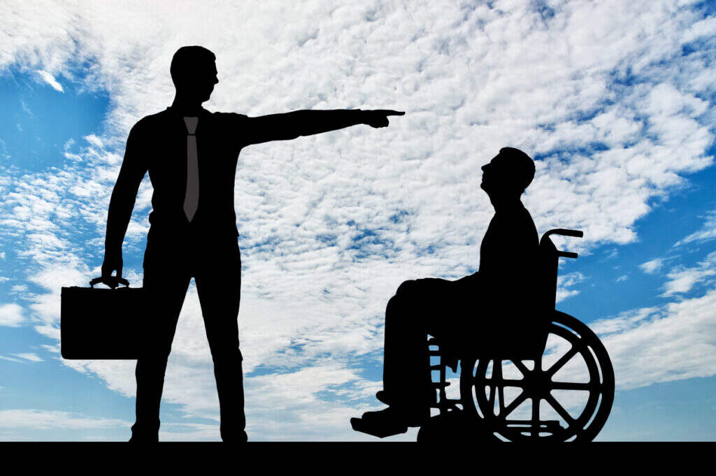 pointing at a person in a wheelchair under a cloudy sky, representing disability discrimination or denial of disability benefits
