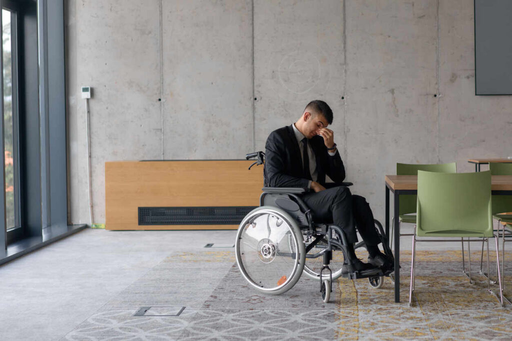 Distressed man in wheelchair, illustrating challenges of total or partial disability policies.