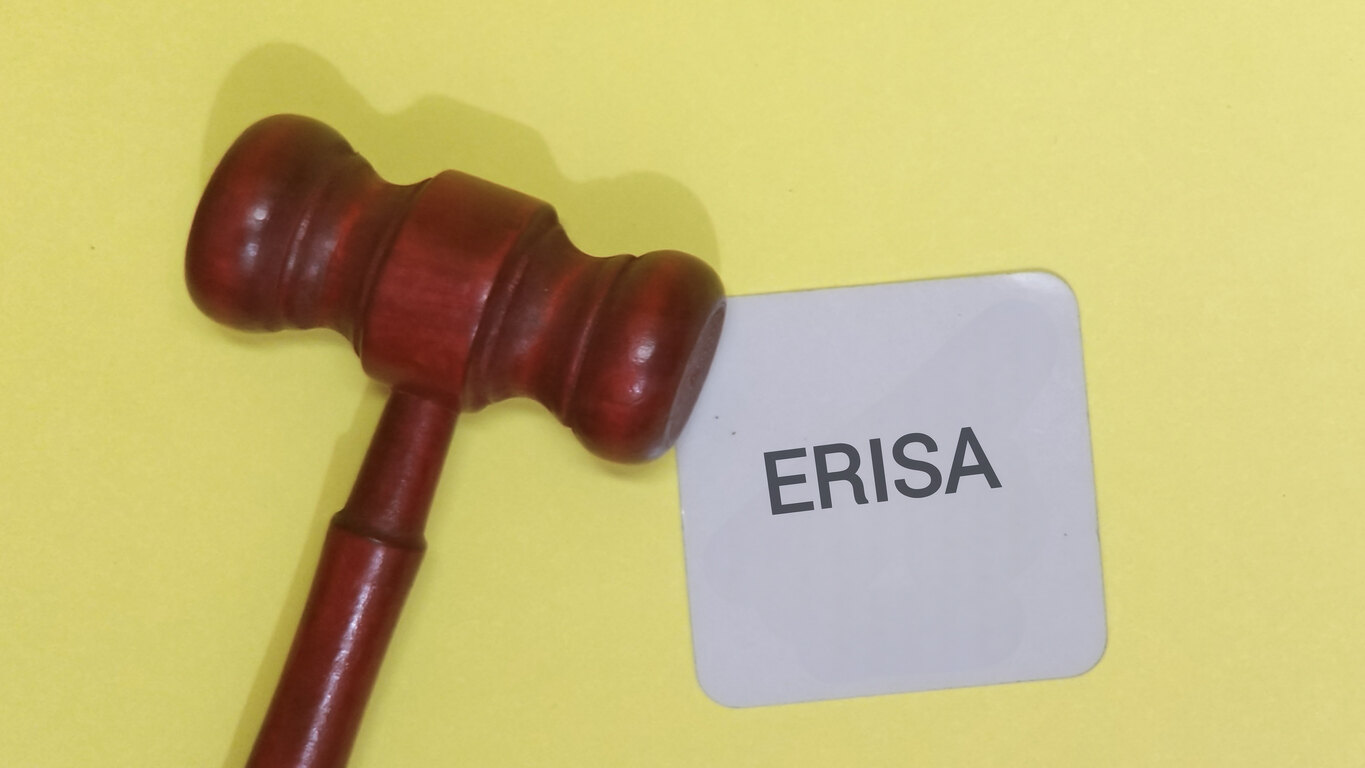 A wooden gavel placed next to a card that reads 'ERISA' on a yellow background, symbolizing the importance of legal assistance when appealing a denied ERISA claim.